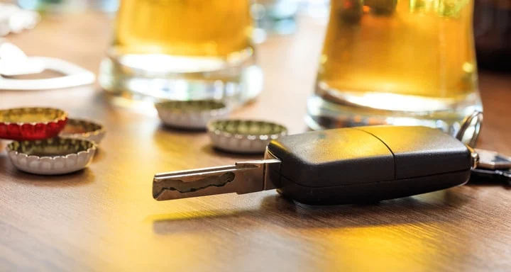 Car keys on a bar beside glasses of beer and bottle caps