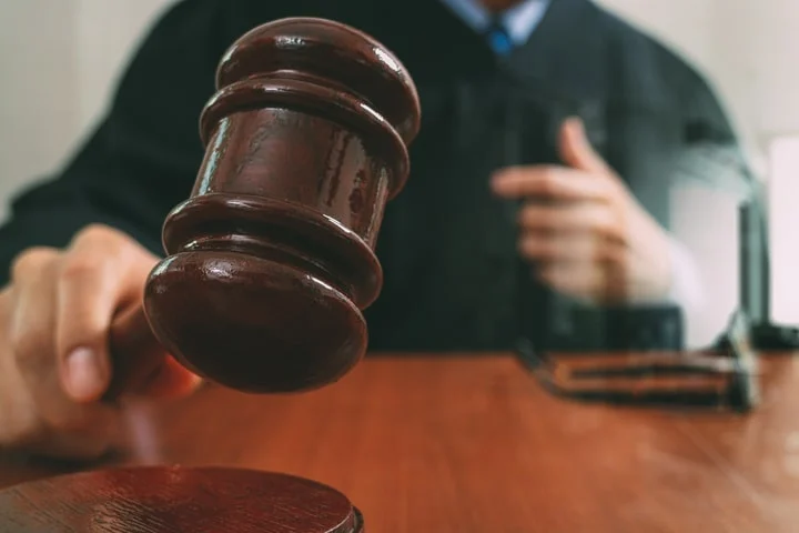 A judge in a black robe raising a wooden gavel