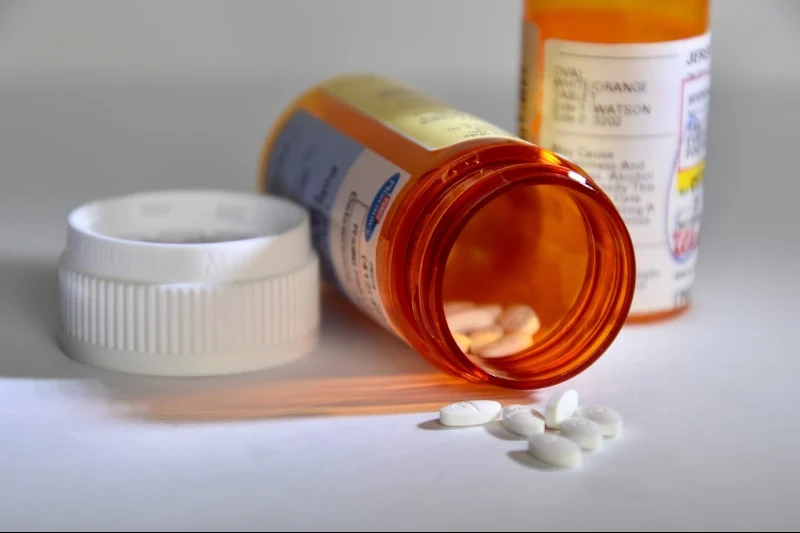 White pills spilling from a tipped-over prescription bottle