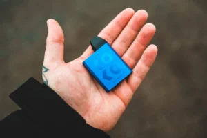 A small blue vape device in the palm of a hand