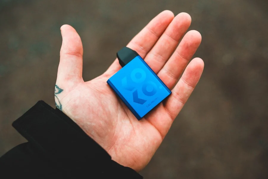 A small blue vape device in the palm of a hand